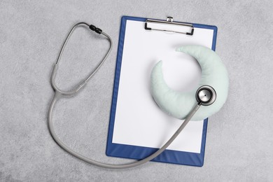 Clipboard, stethoscope and pillow on gray textured background, top view. Children's hospital