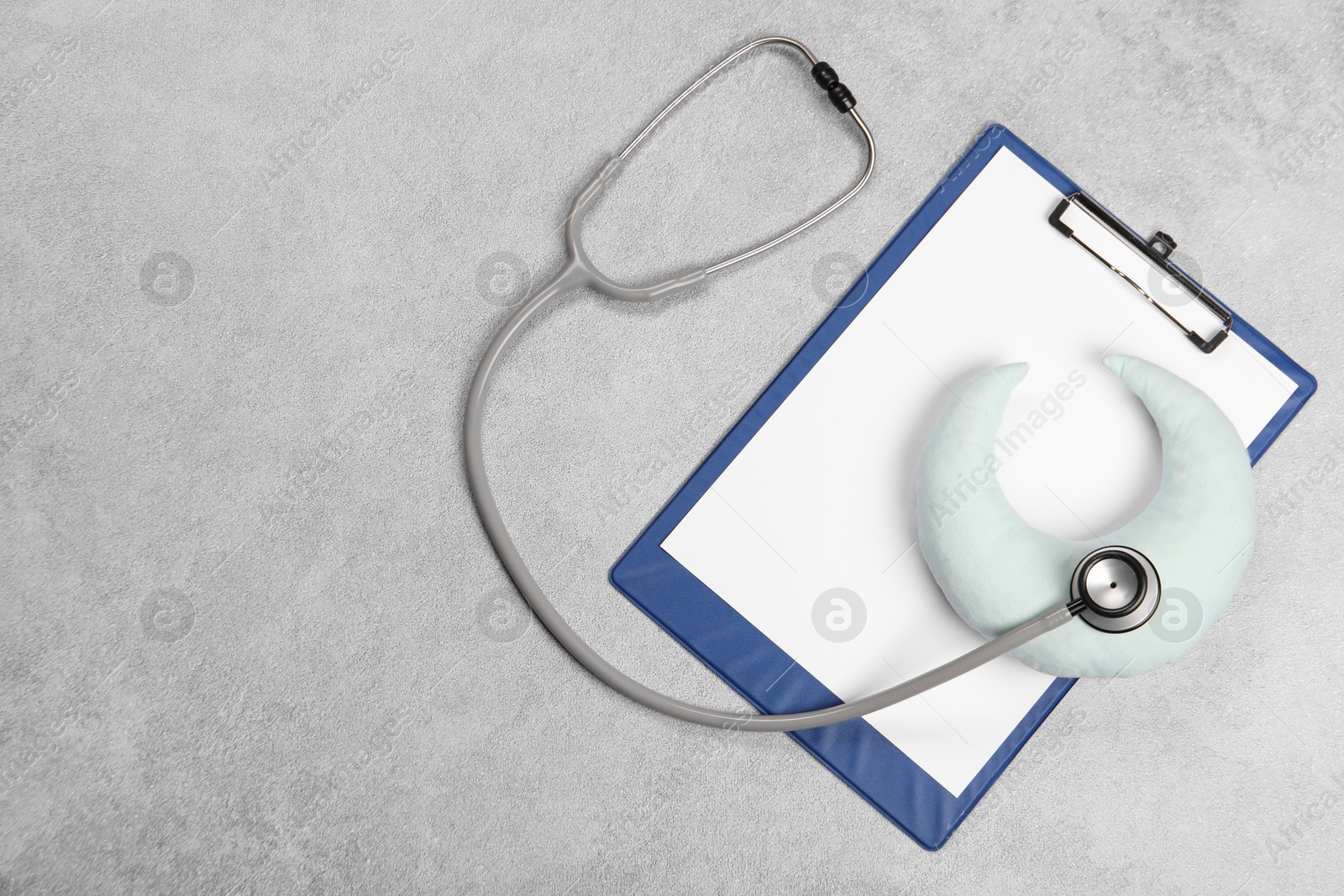 Photo of Clipboard, stethoscope and pillow on gray textured background, top view. Space for text