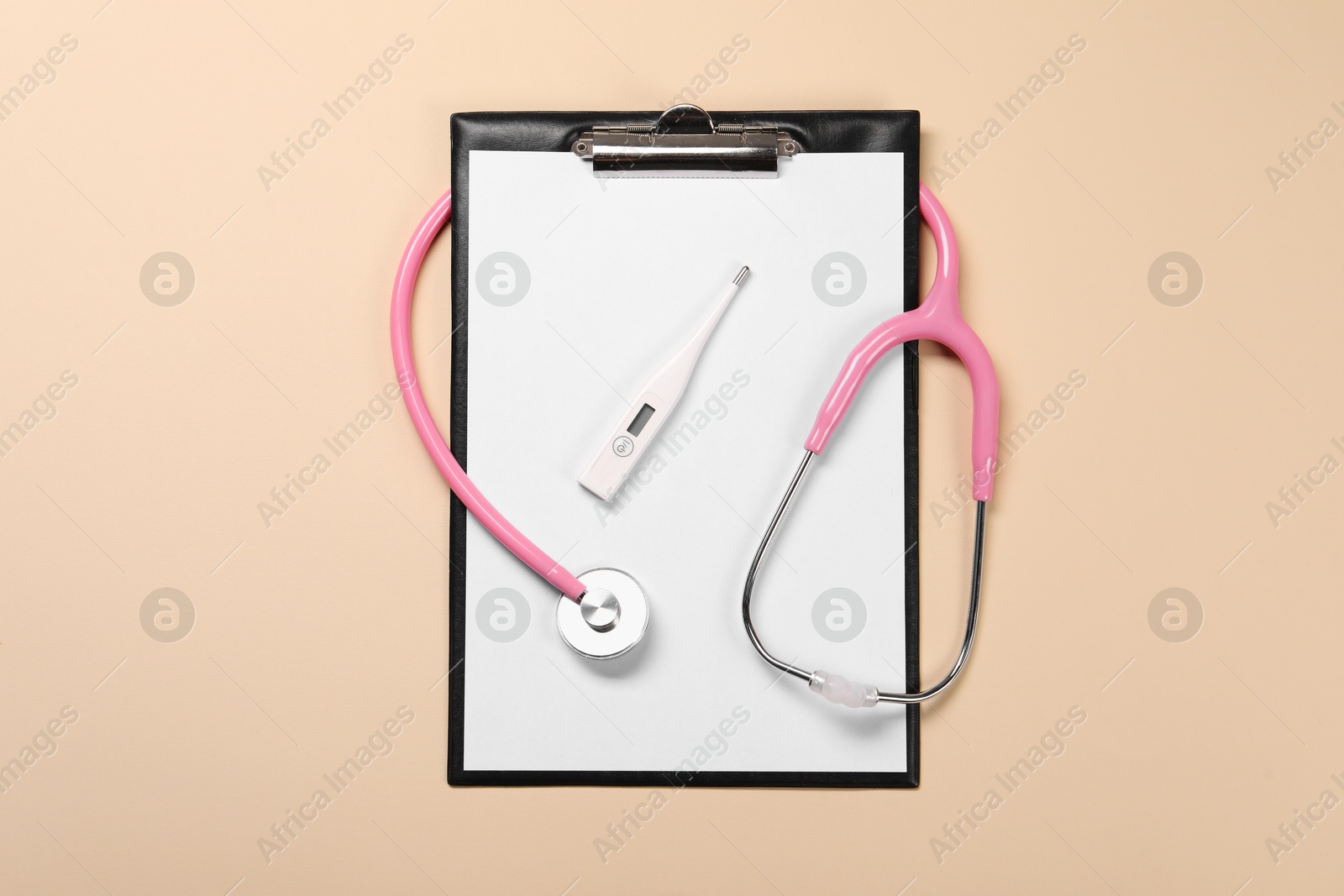 Photo of Clipboard, stethoscope and thermometer on beige background, flat lay. Medical treatment