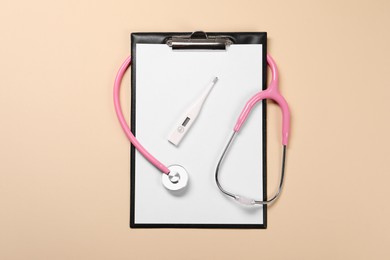 Clipboard, stethoscope and thermometer on beige background, flat lay. Medical treatment