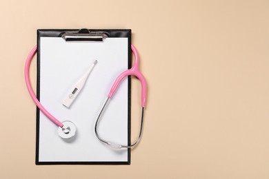 Clipboard, stethoscope and thermometer on beige background, flat lay. Space for text