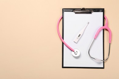 Clipboard, stethoscope and thermometer on beige background, flat lay. Space for text