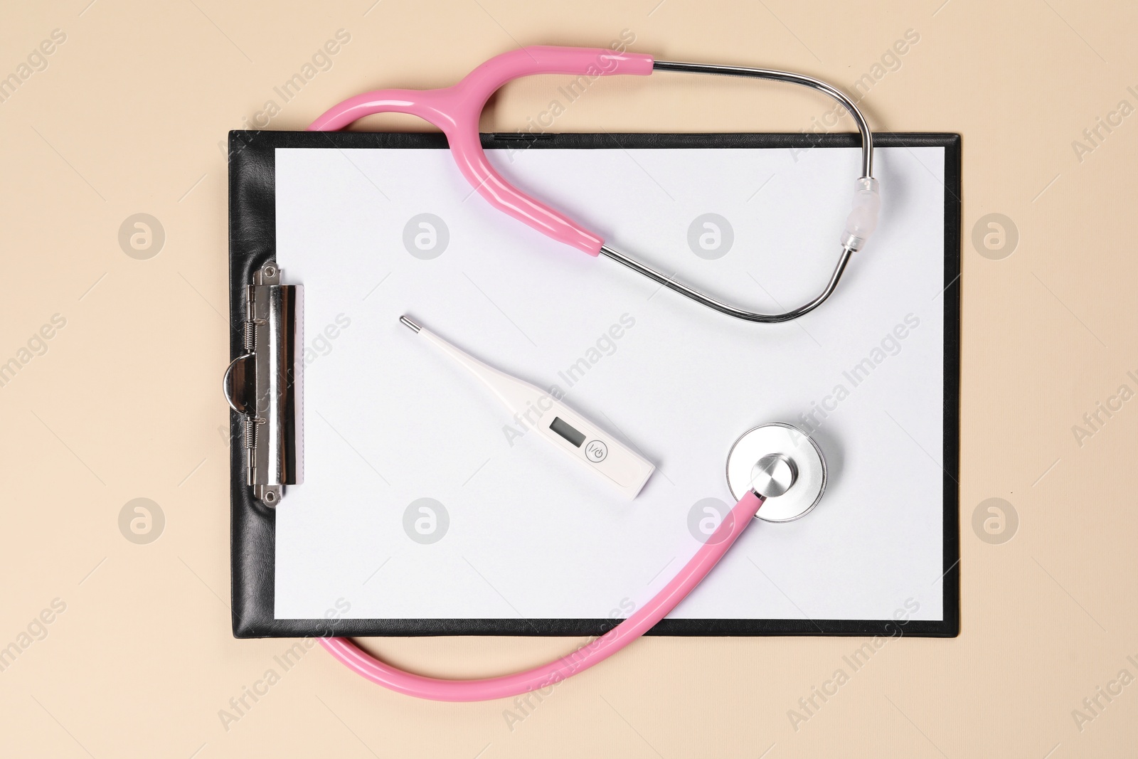 Photo of Clipboard, stethoscope and thermometer on beige background, flat lay. Medical treatment