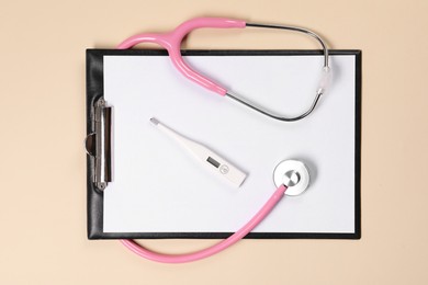 Clipboard, stethoscope and thermometer on beige background, flat lay. Medical treatment