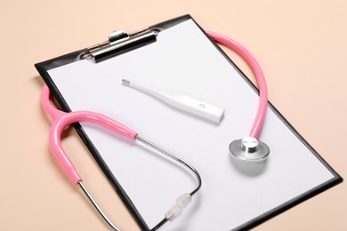 Photo of Clipboard, stethoscope and thermometer on beige background, closeup. Medical treatment