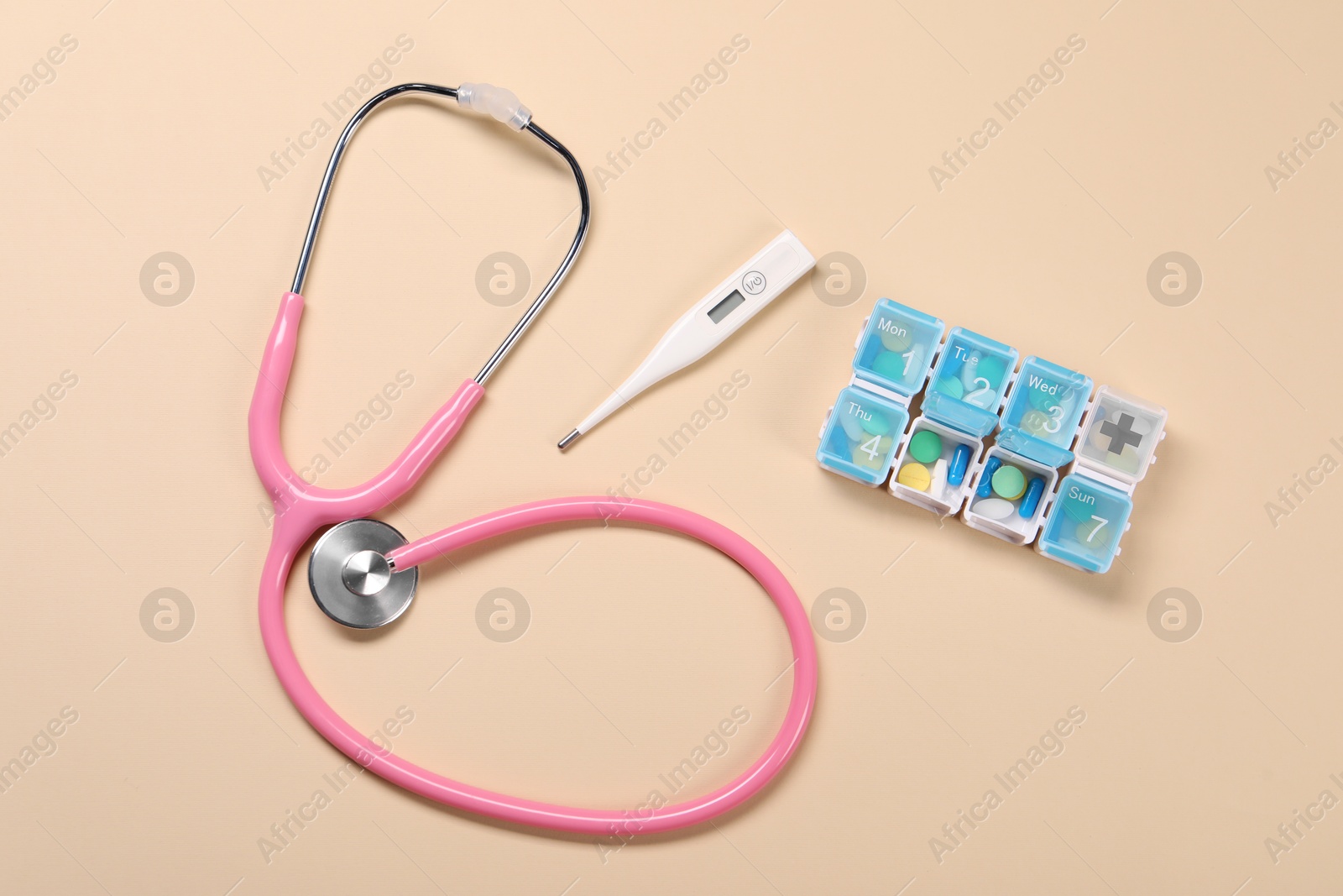 Photo of Stethoscope, thermometer and pills on beige background, flat lay. Medical treatment