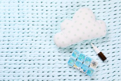 Pillow, pills and nasal spray on light blue blanket, flat lay. Space for text