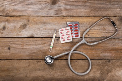 Photo of Stethoscope, thermometer and pills on wooden background, flat lay. Space for text