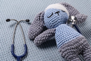 Toy bunny and stethoscope on gray blanket, closeup