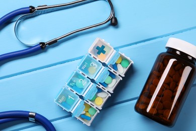 Stethoscope and pills on light blue wooden background, flat lay. Medical treatment