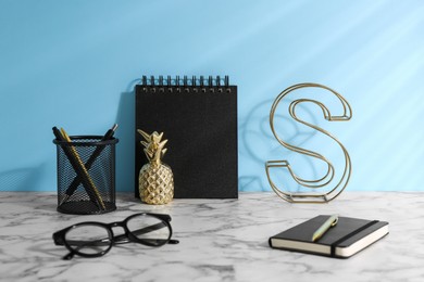 Photo of Stylish office workplace. Decor elements, glasses and stationery on white table near light blue wall