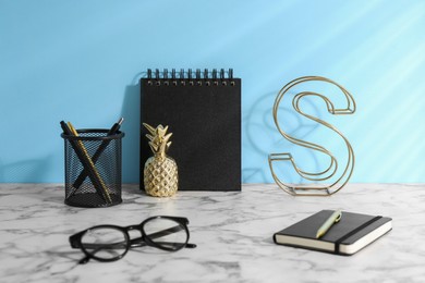 Stylish office workplace. Decor elements, glasses and stationery on white table near light blue wall