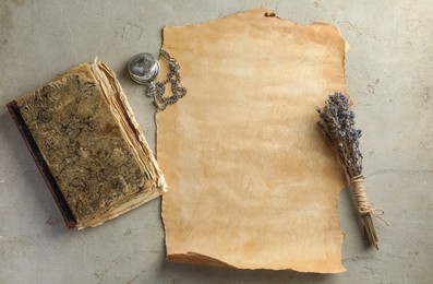 Photo of Sheet of old parchment paper, lavender flowers , vintage book and pocket chain clock on grey table, flat lay