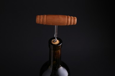 Wine bottle with corkscrew on dark background, closeup