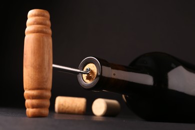 Wine bottle with corkscrew on dark background, closeup