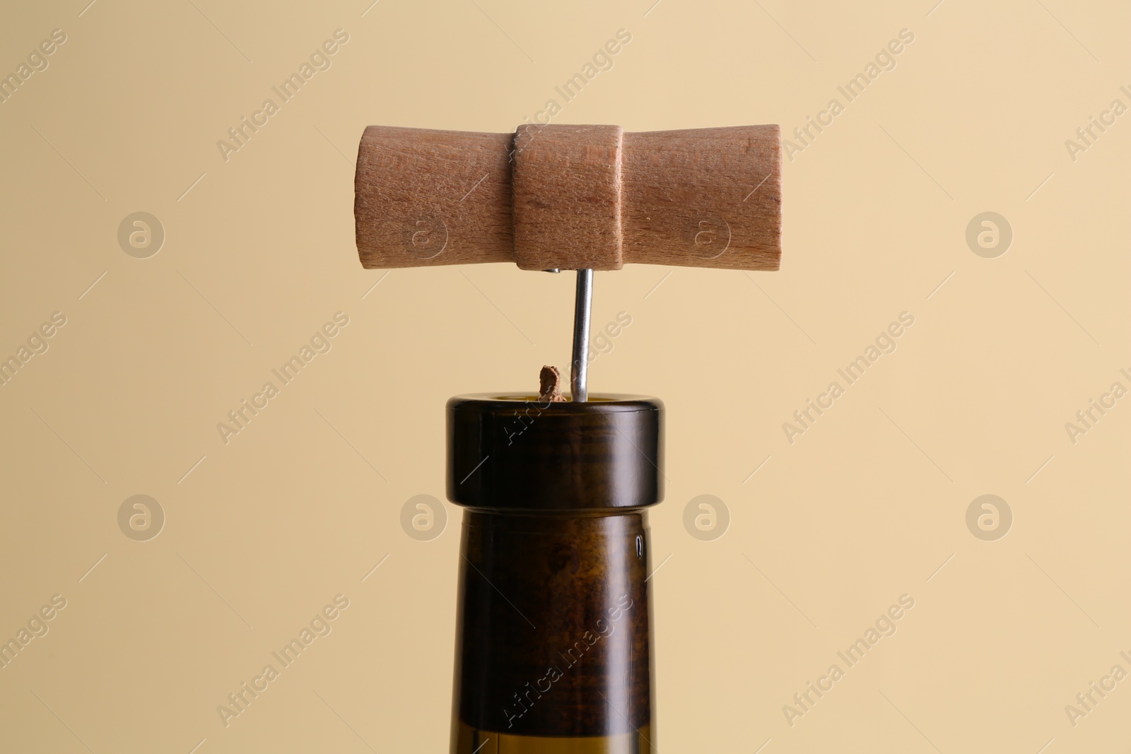 Photo of Wine bottle with corkscrew on beige background, closeup