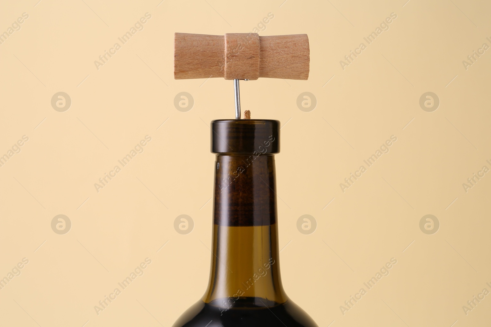 Photo of Wine bottle with corkscrew on beige background, closeup