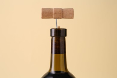 Photo of Wine bottle with corkscrew on beige background, closeup