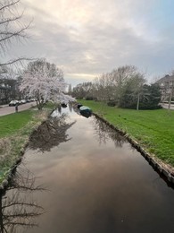 Picturesque view of canal with moored boats and blossoming trees in spring