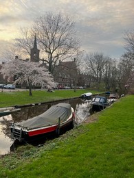 Picturesque view of canal with moored boats and blossoming trees in spring