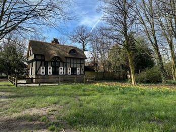 Photo of Picturesque view of house and trees in park under blue sky