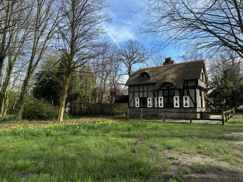 Photo of Picturesque view of house and trees in park under blue sky