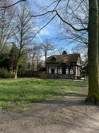 Photo of Picturesque view of house and trees in park under blue sky