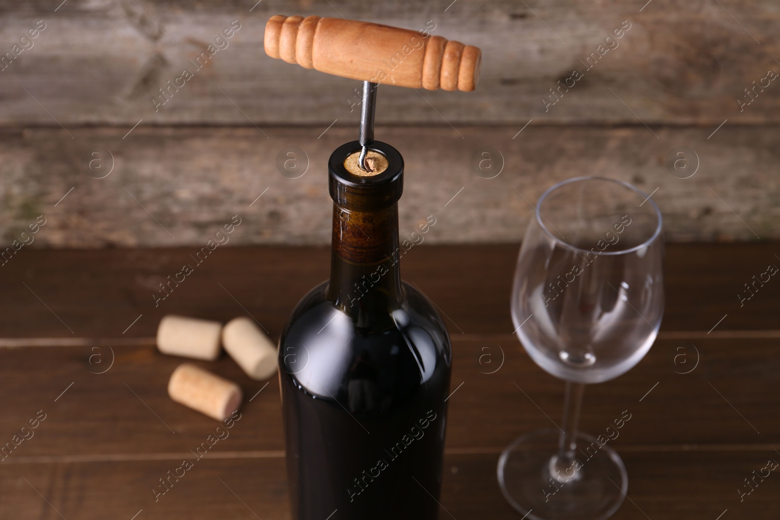 Photo of Wine bottle with corkscrew and glass on wooden table