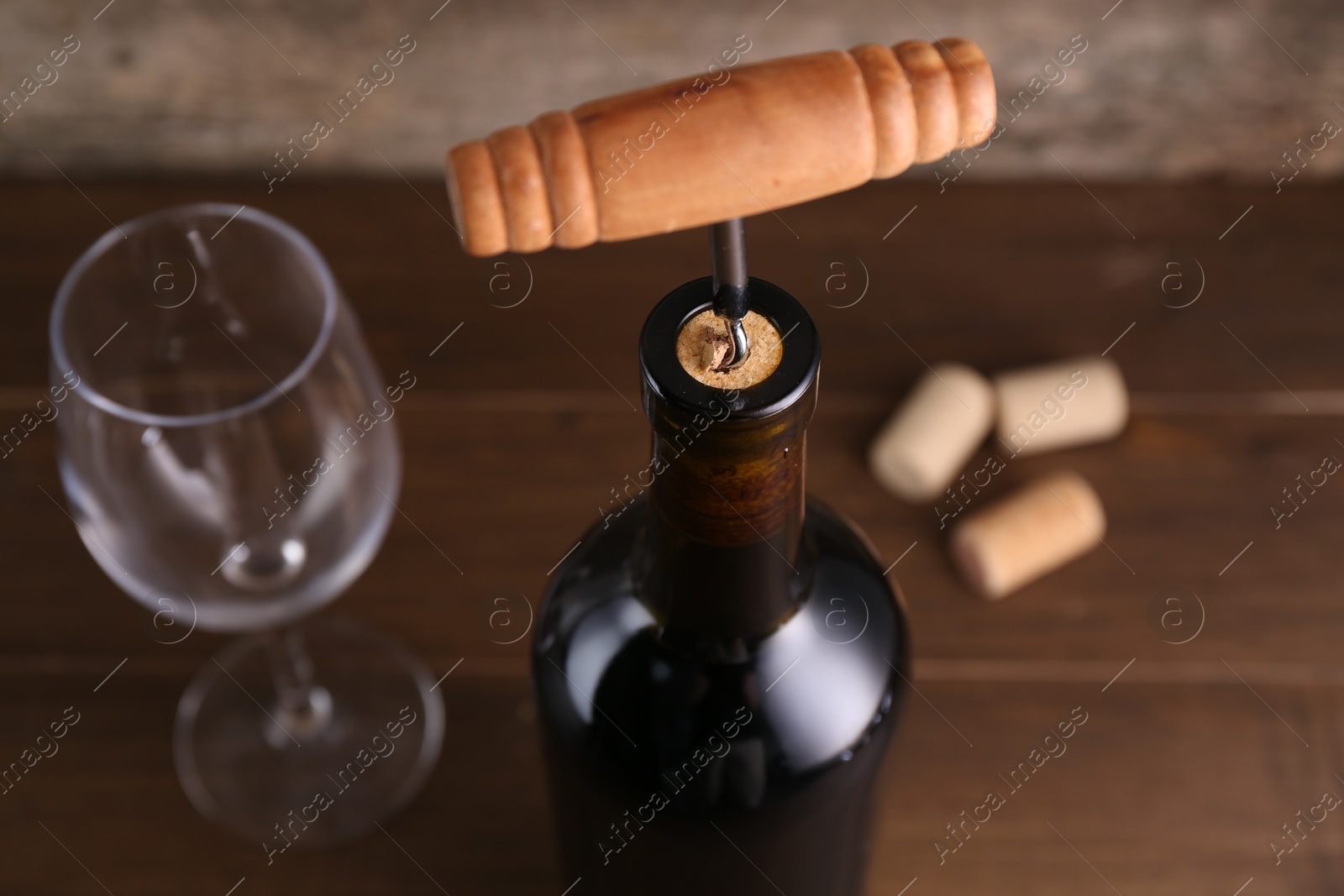 Photo of Wine bottle with corkscrew on table, closeup