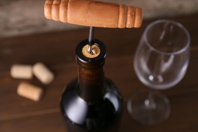 Photo of Wine bottle with corkscrew on table, closeup