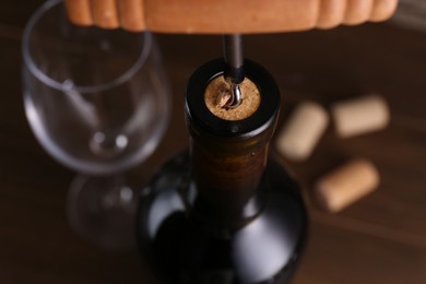 Wine bottle with corkscrew on table, closeup