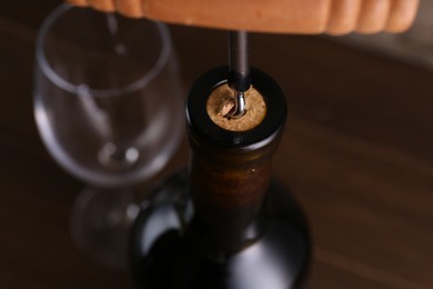 Photo of Wine bottle with corkscrew on table, closeup