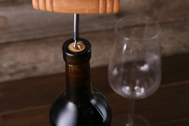 Wine bottle with corkscrew on table, closeup