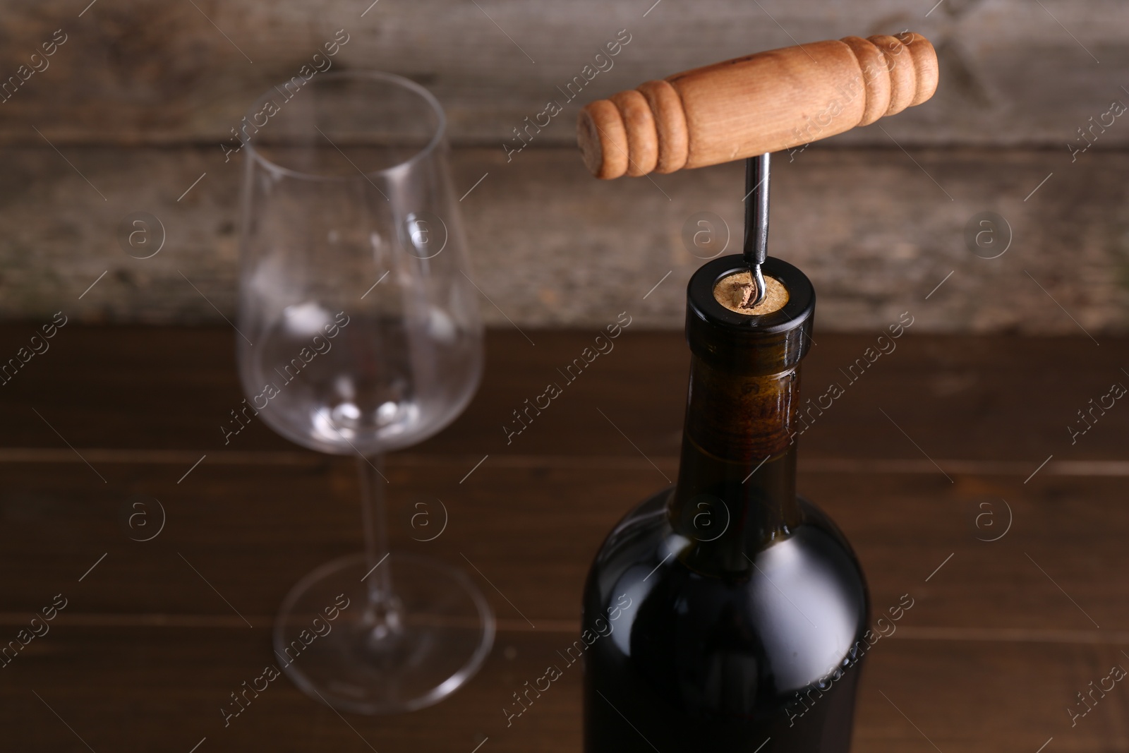 Photo of Wine bottle with corkscrew on table, closeup