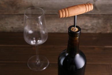 Wine bottle with corkscrew on table, closeup