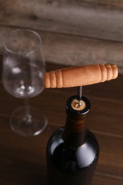 Photo of Wine bottle with corkscrew on table, closeup