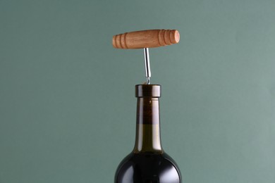 Wine bottle with corkscrew on grey background