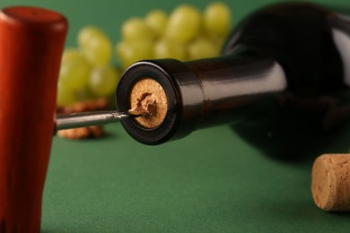 Photo of Wine bottle with corkscrew on green background, closeup