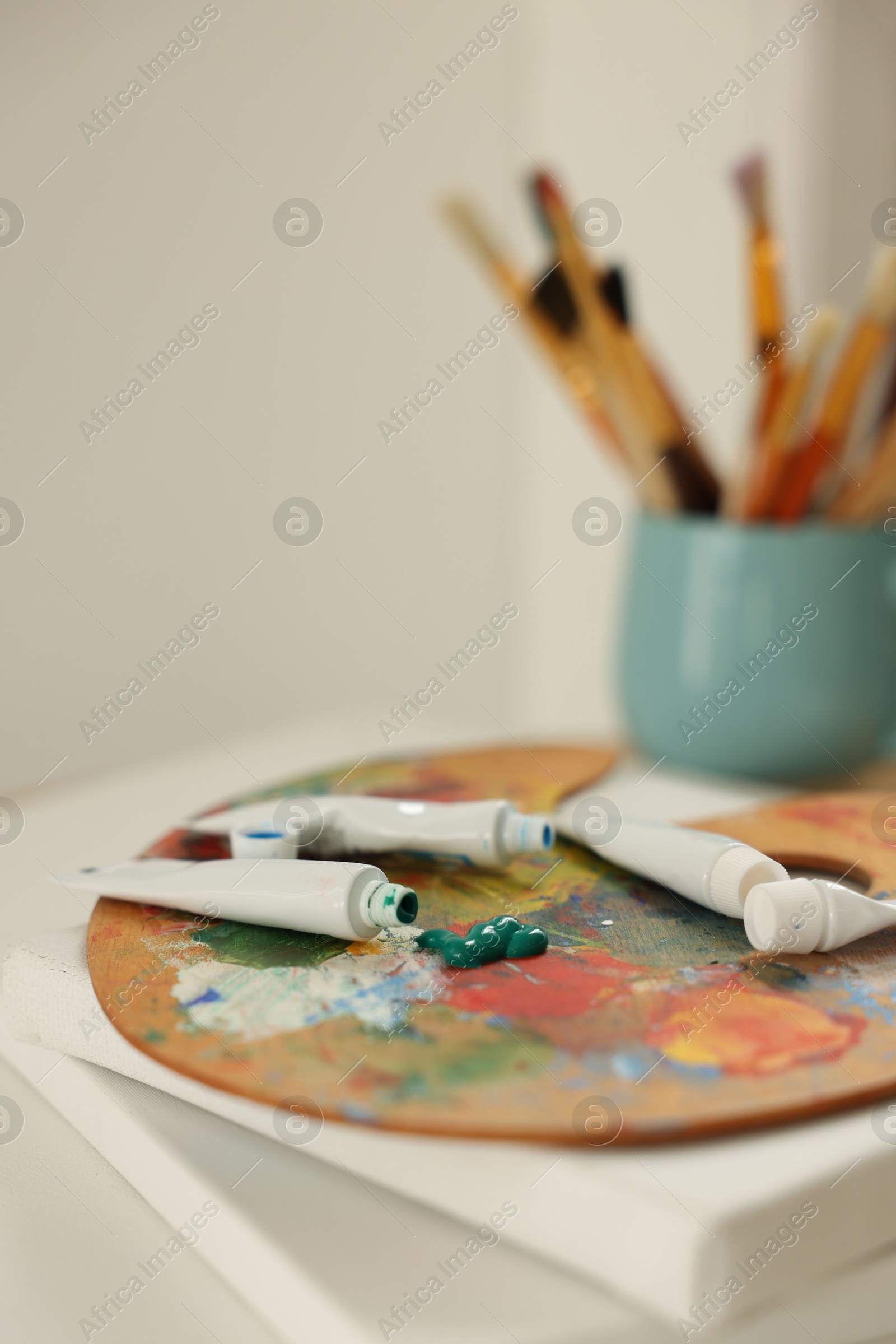 Photo of Artist's palette and paints on blank canvases indoors, closeup