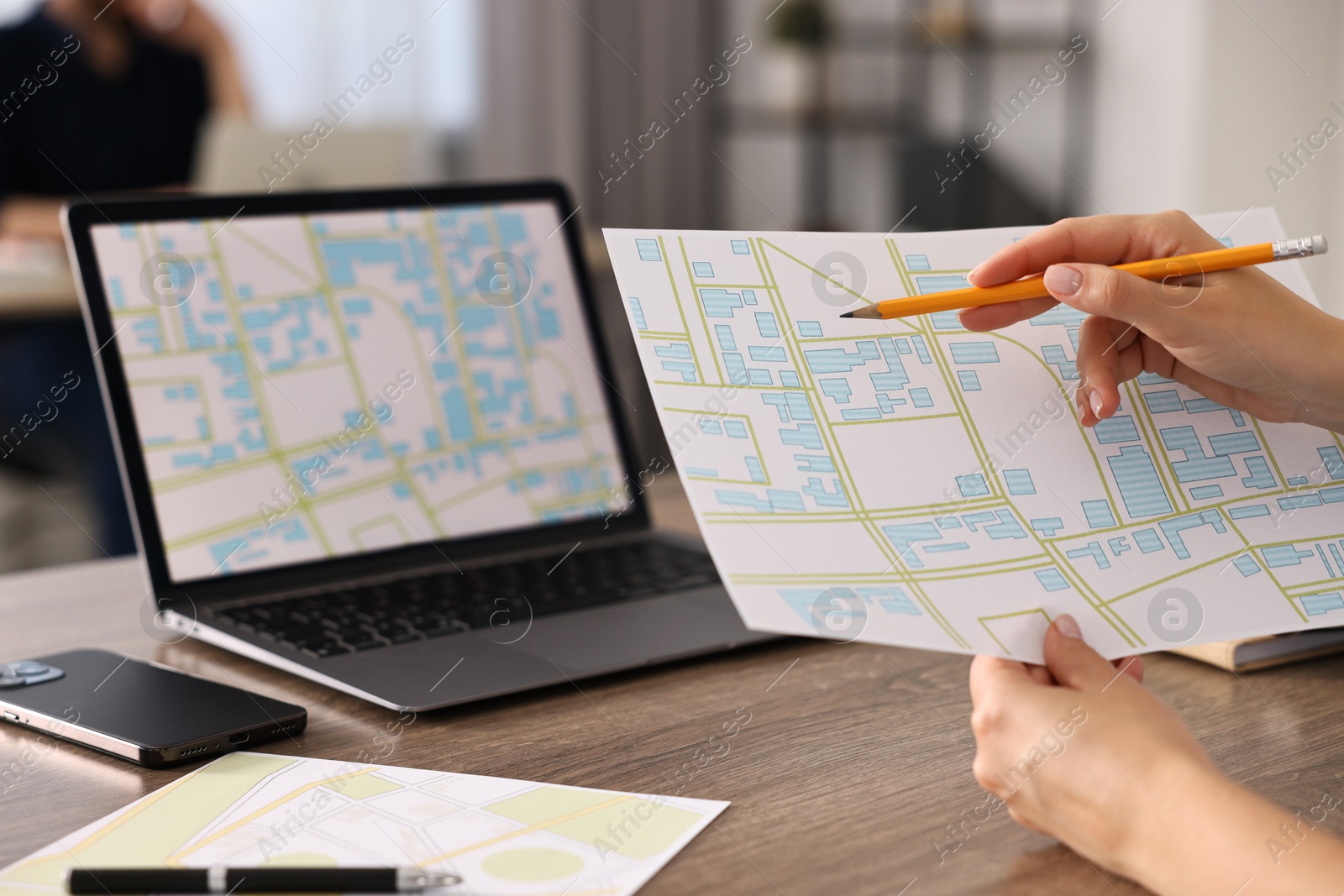 Photo of Cartographer working with cadastral maps at wooden table in office, closeup