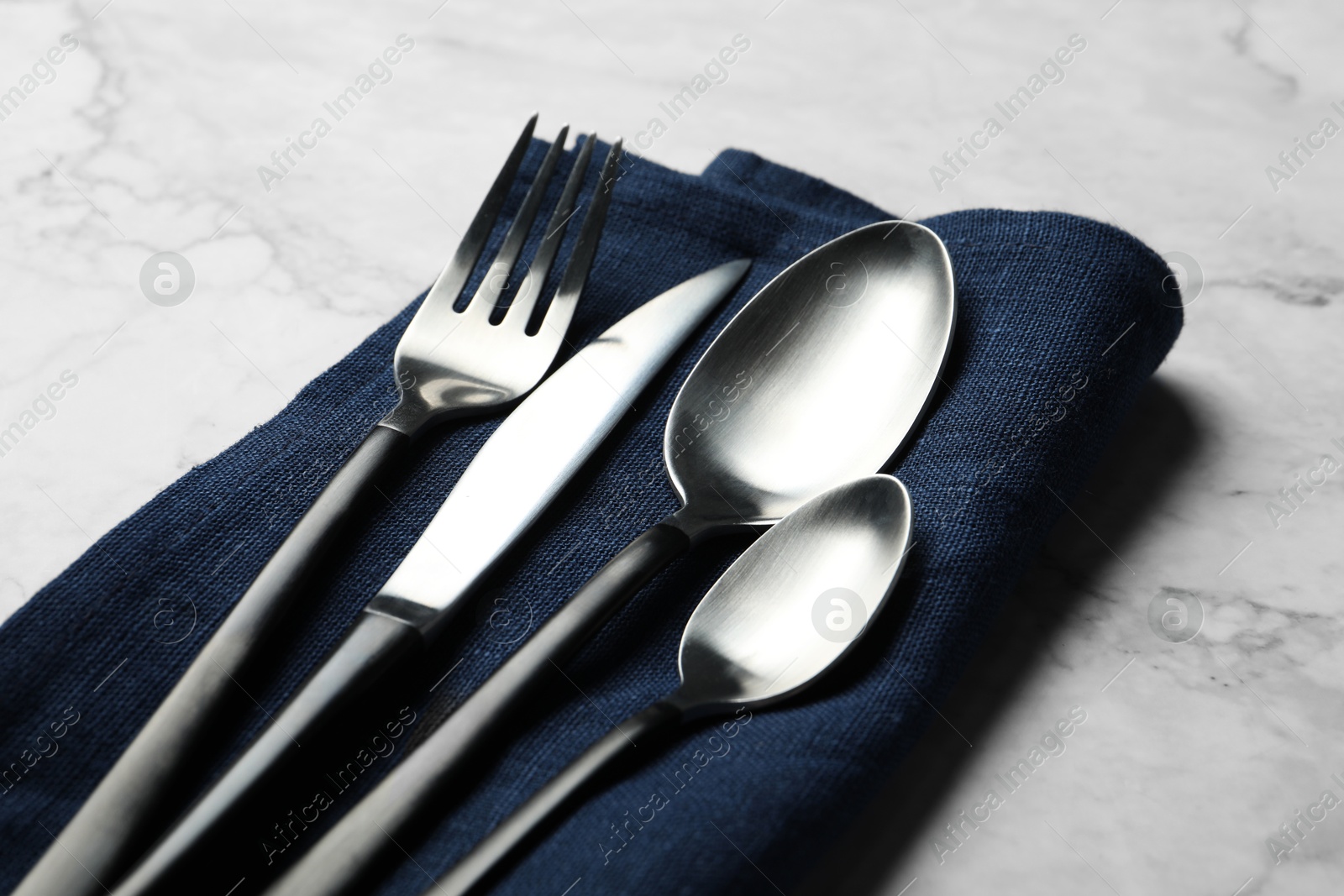 Photo of Stylish cutlery and napkin on white marble table