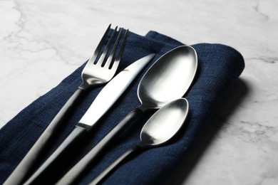 Photo of Stylish cutlery and napkin on white marble table