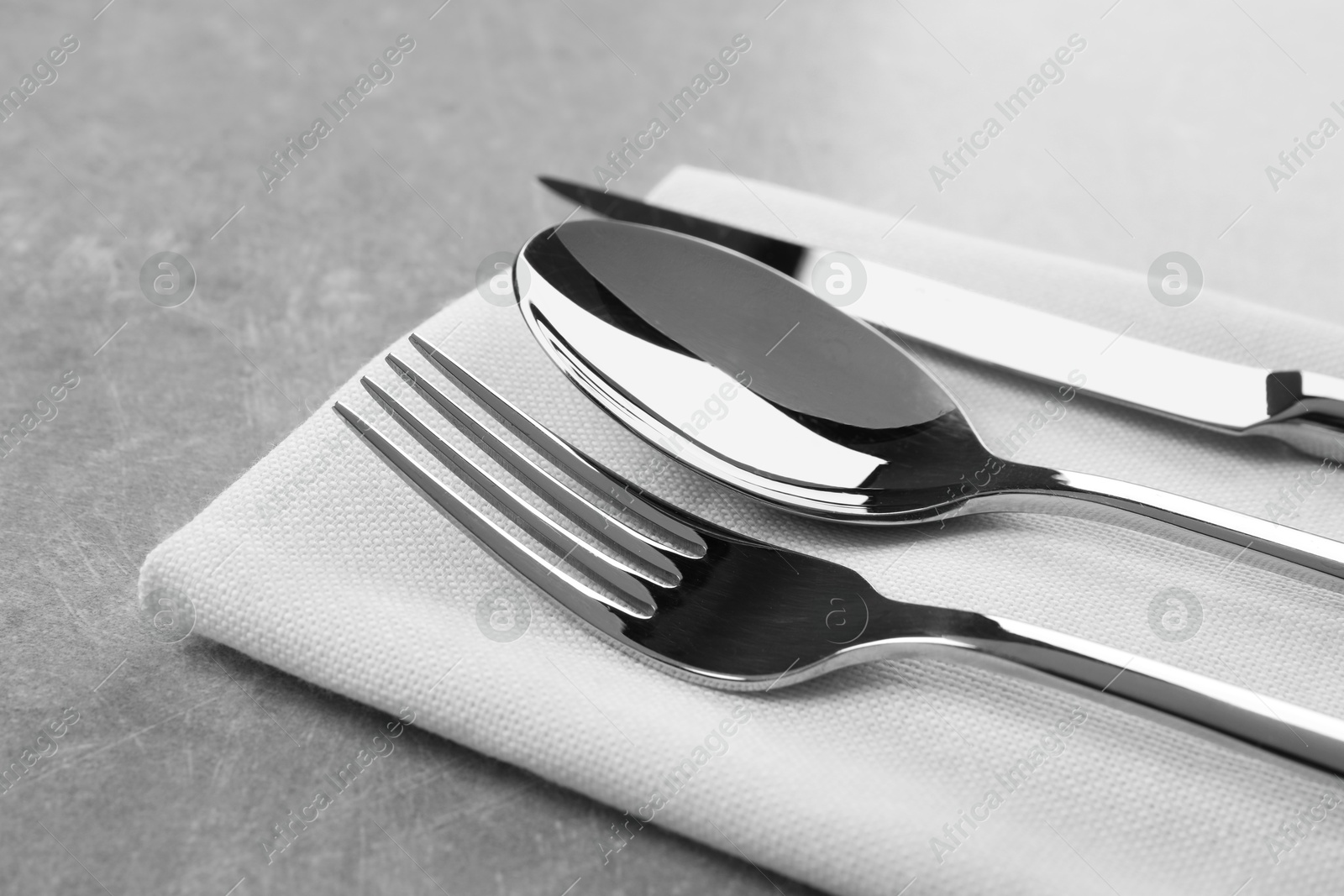 Photo of Stylish cutlery set and napkin on grey table, closeup