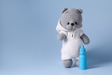 Photo of Toy bear and nasal spray on light blue background, space for text