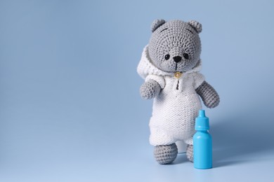 Toy bear and nasal spray on light blue background, space for text