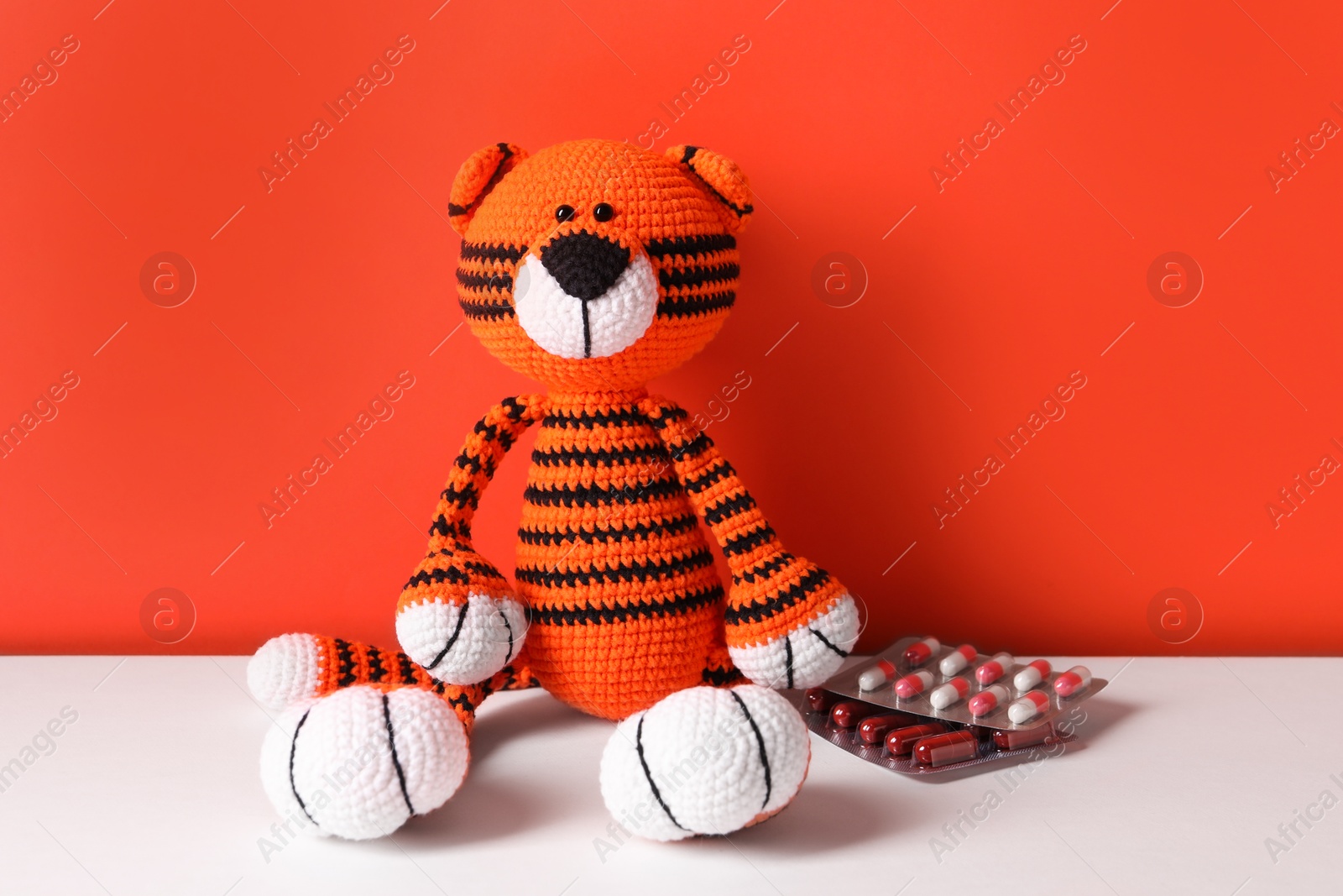Photo of Toy tiger and pills on color background