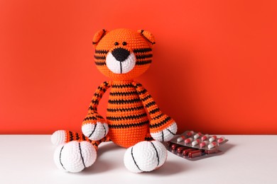 Photo of Toy tiger and pills on color background