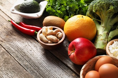 Photo of Healthy meal. Different vegetables and raw eggs on wooden table, closeup