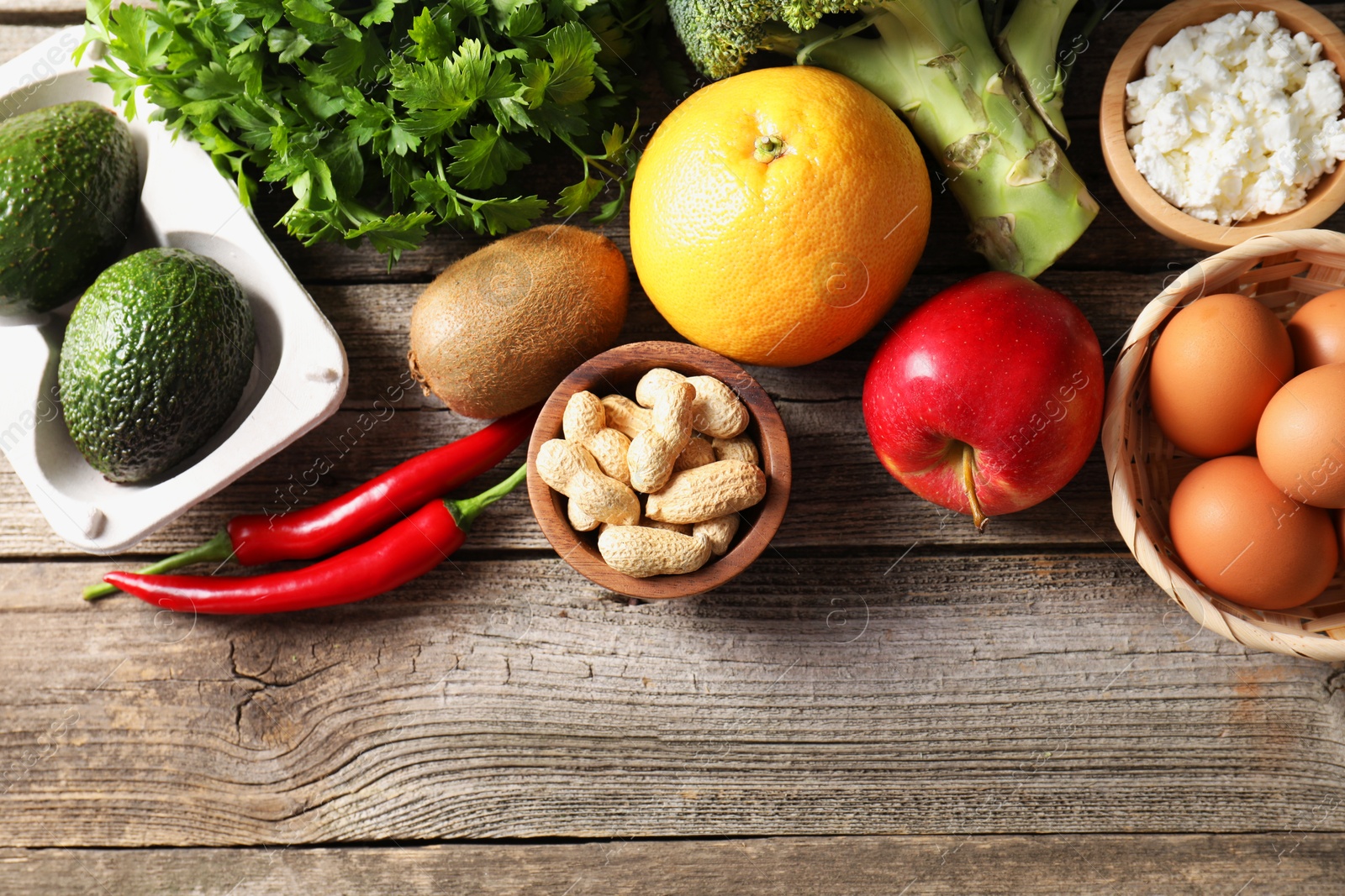 Photo of Healthy meal. Different vegetables and raw eggs on wooden table, flat lay. Space for text