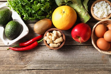 Photo of Healthy meal. Different vegetables and raw eggs on wooden table, flat lay. Space for text